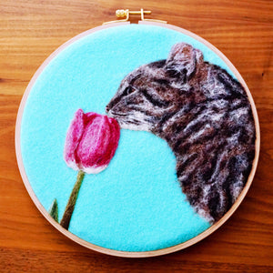 Wool painting of a cat smelling a tulip