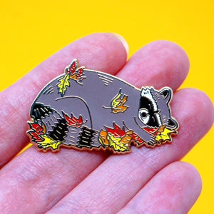 Sleeping raccoon in fall leaves enamel pin
